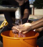 african-woman-pouring-water-recipient-outdoors