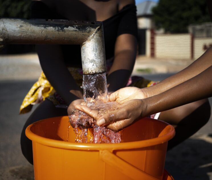 african-woman-pouring-water-recipient-outdoors